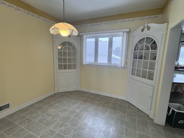unfurnished dining area with dark tile patterned flooring, visible vents, and a wealth of natural light
