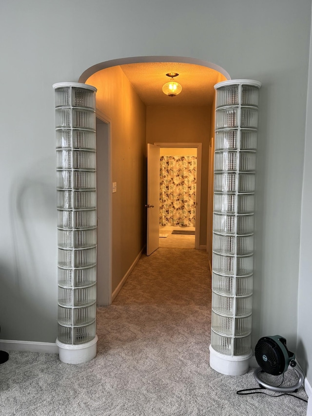 hall with baseboards, arched walkways, and carpet
