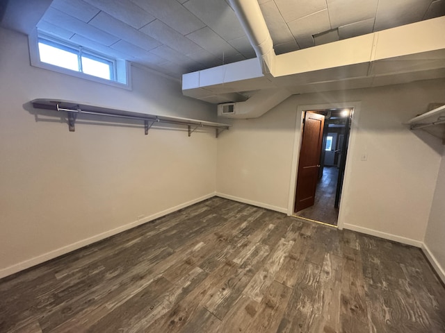 below grade area with dark wood finished floors, baseboards, and visible vents