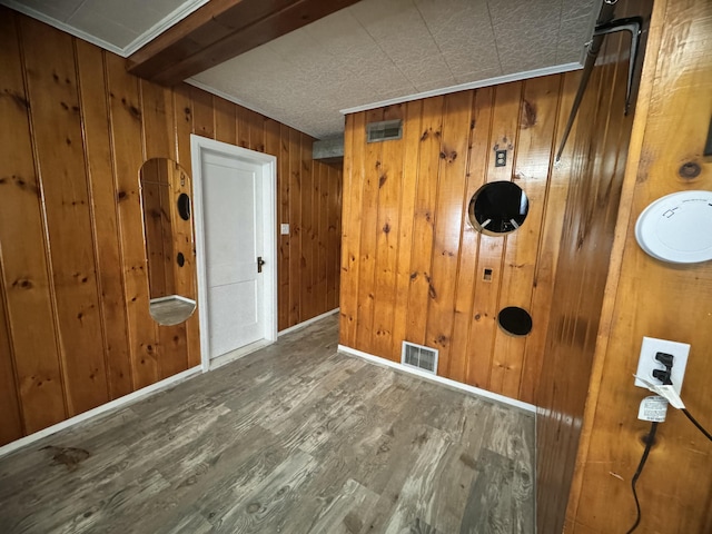 interior space with baseboards, wood finished floors, visible vents, and wooden walls