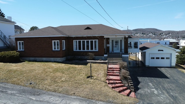 single story home with a front lawn, driveway, an outbuilding, a garage, and roof with shingles