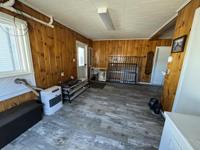 misc room featuring wood walls, electric panel, heating unit, and wood finished floors