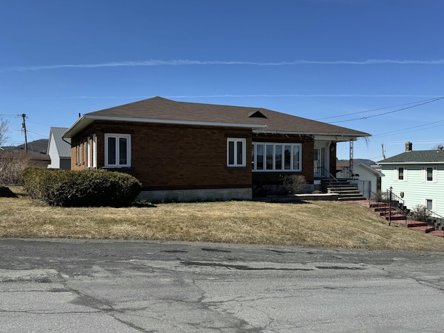 view of side of property featuring brick siding and roof with shingles