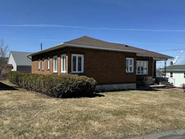 view of home's exterior with brick siding and a lawn