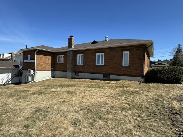 back of house with a lawn, brick siding, and a chimney