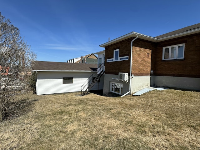 rear view of property featuring stairway, a lawn, and brick siding