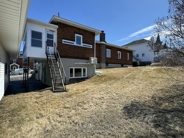rear view of property featuring a chimney, brick siding, and stairs