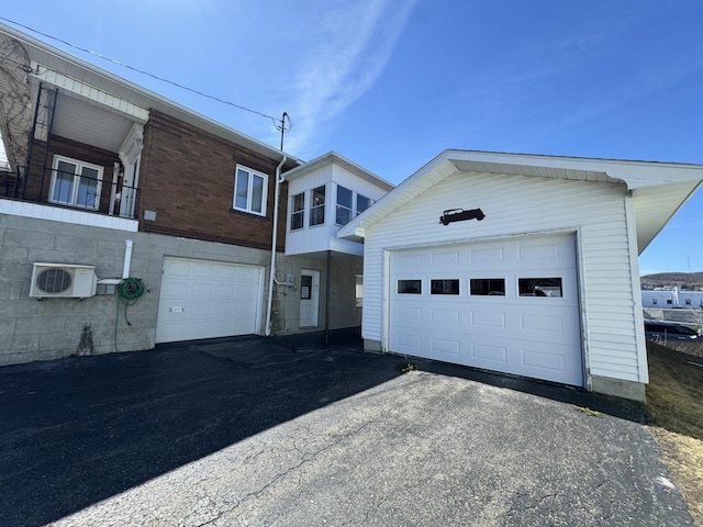 exterior space featuring a garage, driveway, ac unit, and an outbuilding