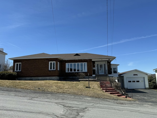single story home with brick siding, a detached garage, and aphalt driveway