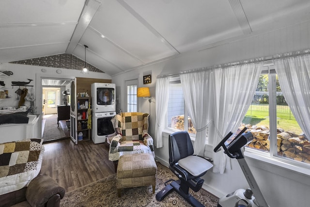 living room featuring vaulted ceiling, stacked washer and dryer, and dark wood-style floors