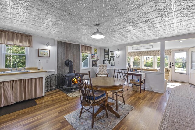 dining area with an ornate ceiling, a wood stove, and wood finished floors