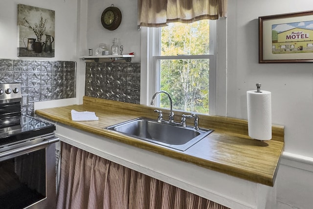 kitchen with backsplash, electric stove, and a sink
