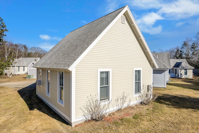 view of side of home with cooling unit, a lawn, and roof with shingles