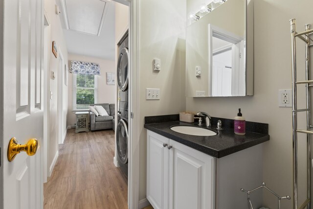 bathroom with stacked washer / drying machine, baseboards, wood finished floors, and vanity