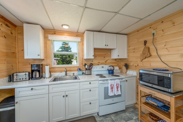 43 W Shore Rd, Harpswell, ME 04003 - kitchen with wood walls, white range with electric stovetop, a sink, stainless steel microwave, and white cabinetry