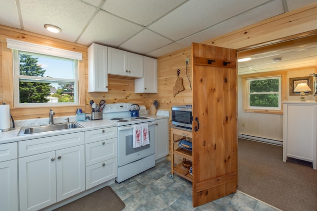 43 W Shore Rd, Harpswell, ME 04003 - kitchen with white electric stove, wooden walls, stainless steel microwave, a baseboard radiator, and white cabinetry