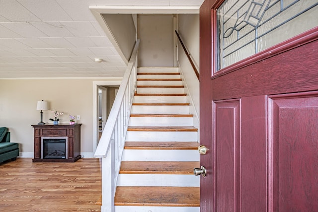 stairs featuring baseboards, wood finished floors, and a fireplace
