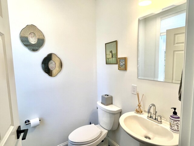 bathroom with a sink, baseboards, and toilet