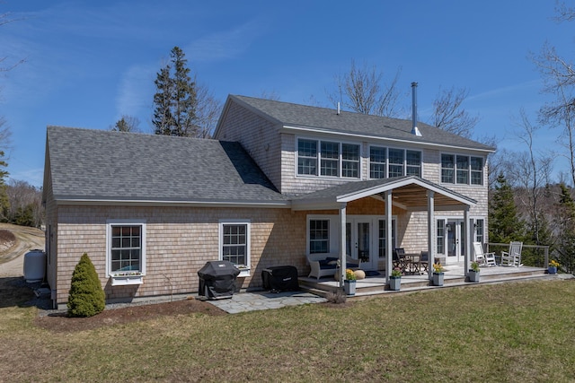 rear view of property featuring a lawn, a patio, french doors, and roof with shingles