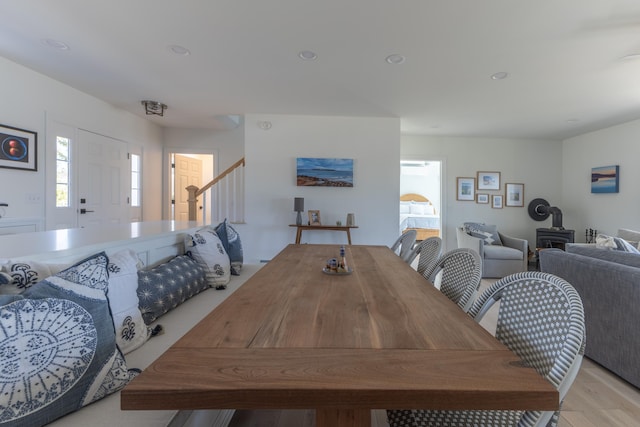 dining room with recessed lighting, light wood-type flooring, a wood stove, and stairs