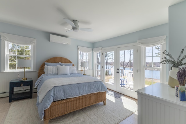 bedroom featuring french doors, light wood-type flooring, an AC wall unit, a water view, and access to outside