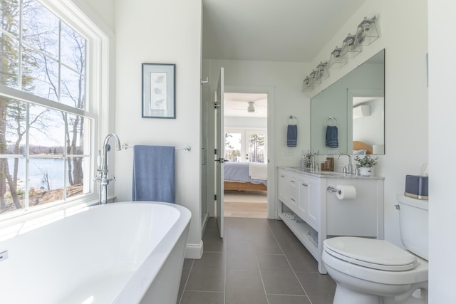 full bath with ceiling fan, a freestanding bath, tile patterned flooring, toilet, and ensuite bathroom