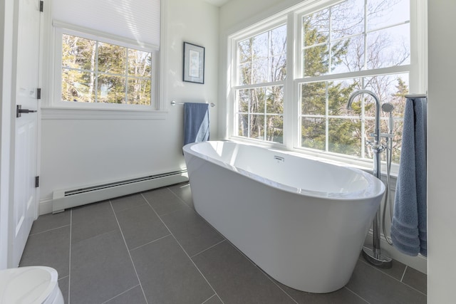 bathroom featuring a freestanding tub, a baseboard radiator, toilet, and tile patterned flooring