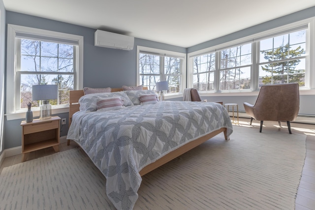 bedroom featuring a baseboard radiator, multiple windows, a wall mounted AC, and wood finished floors