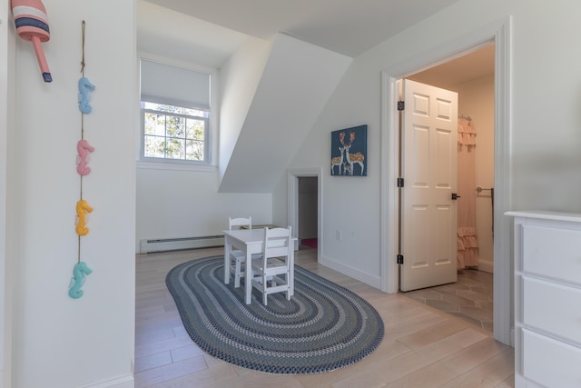 additional living space with baseboards, baseboard heating, and light wood-style flooring