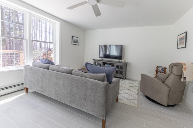 living area featuring a baseboard radiator, baseboards, and ceiling fan