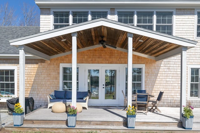 property entrance featuring a ceiling fan, roof with shingles, a wooden deck, and french doors