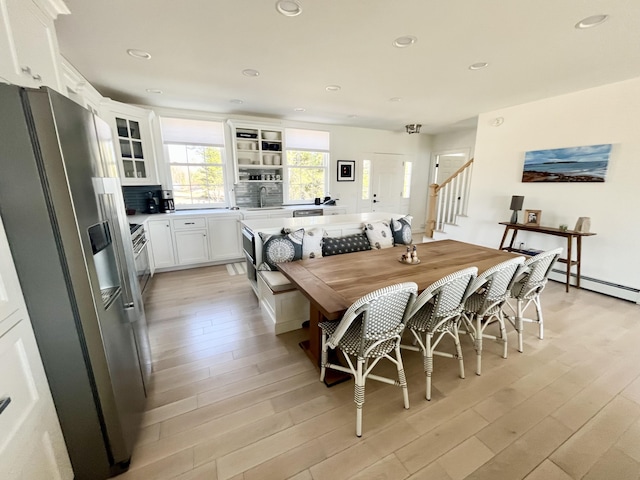dining room featuring a baseboard heating unit, recessed lighting, light wood-style flooring, and stairs
