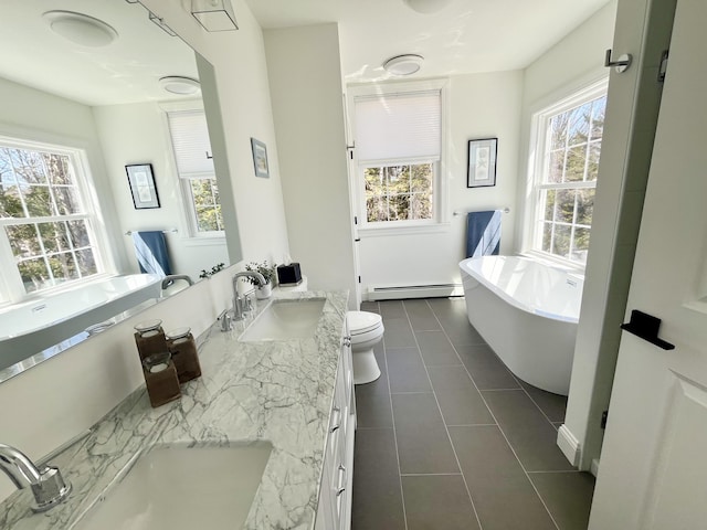 bathroom with tile patterned flooring, double vanity, a baseboard radiator, a soaking tub, and a sink