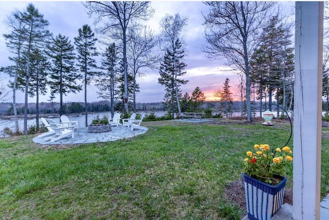 yard at dusk with a water view and a patio