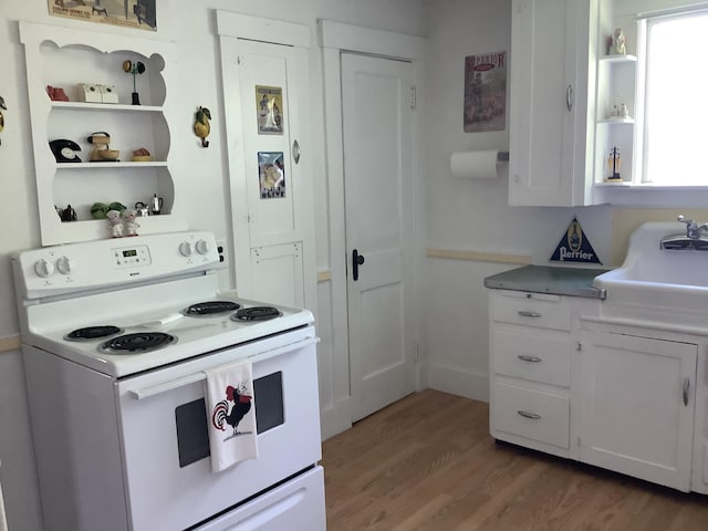 kitchen with white electric range oven, open shelves, a sink, light wood-style flooring, and white cabinetry