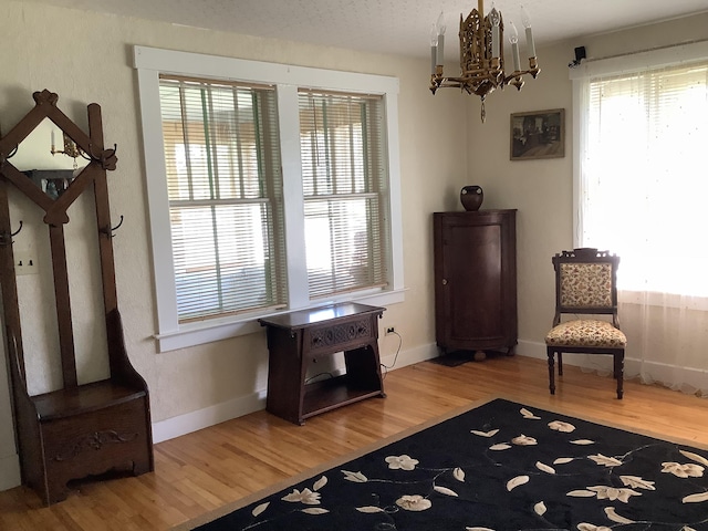 living area featuring baseboards, wood finished floors, and a notable chandelier