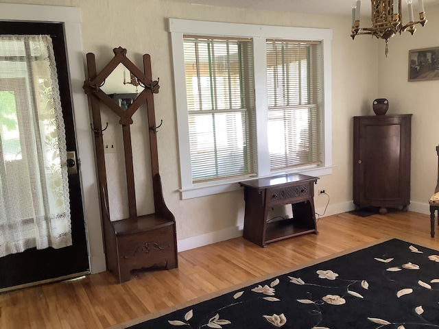 entryway featuring an inviting chandelier, wood finished floors, and baseboards