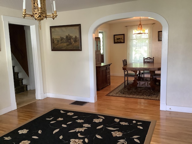 dining area featuring a chandelier, arched walkways, light wood finished floors, and baseboards