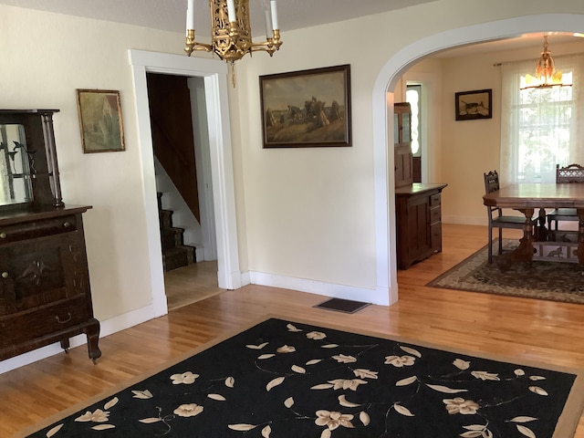 dining area featuring light wood-style flooring, arched walkways, visible vents, baseboards, and an inviting chandelier