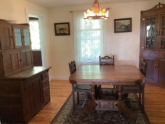 dining space featuring baseboards, a notable chandelier, and light wood-style floors