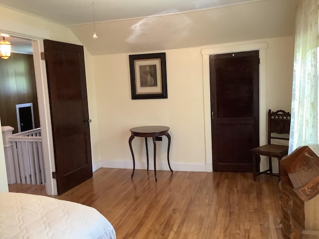 bedroom featuring baseboards, vaulted ceiling, and wood finished floors