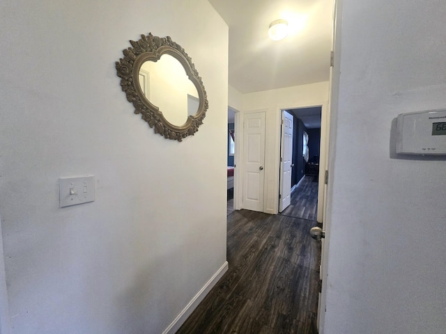 corridor with dark wood finished floors and baseboards