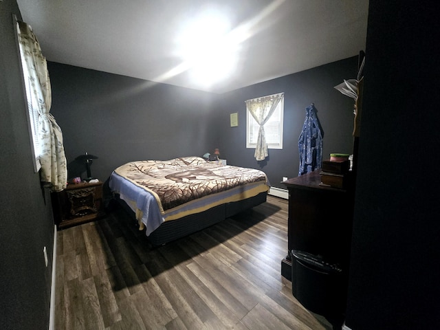 bedroom with wood finished floors and a baseboard radiator