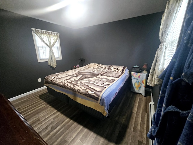 bedroom with baseboards, wood finished floors, and multiple windows