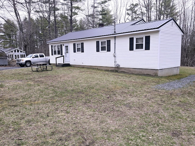 view of front of property featuring entry steps, a front yard, and metal roof