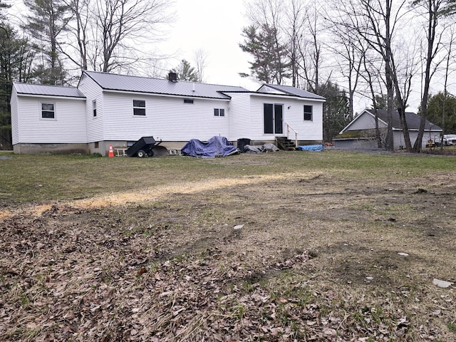rear view of property with a chimney, entry steps, and metal roof
