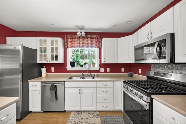 95 The Woods Rd, Union, ME 04862 - kitchen featuring appliances with stainless steel finishes, white cabinetry, light wood finished floors, glass insert cabinets, and light countertops