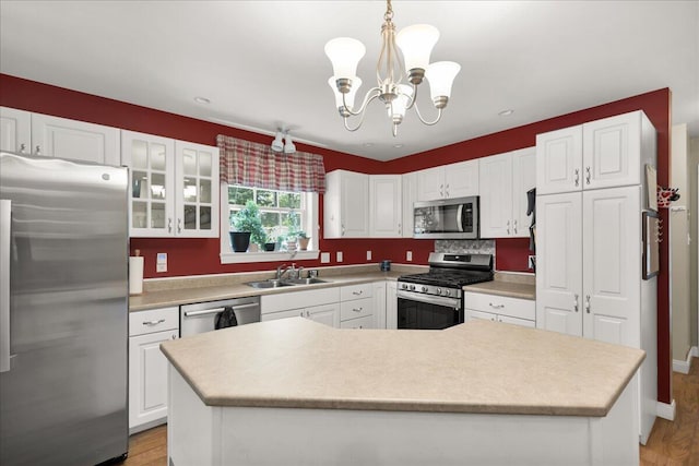 95 The Woods Rd, Union, ME 04862 - kitchen featuring stainless steel appliances, white cabinetry, light wood-type flooring, and a chandelier