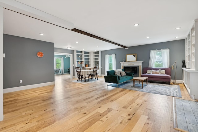 1228 Long Plains Rd, Buxton, ME 04093 - living room featuring light wood-type flooring, beam ceiling, a glass covered fireplace, recessed lighting, and built in shelves