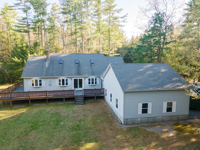 rear view of property featuring a chimney, roof with shingles, a lawn, and a deck